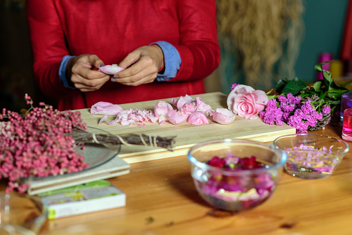 Woman with knife chopping flower petals in perfumery workshop
