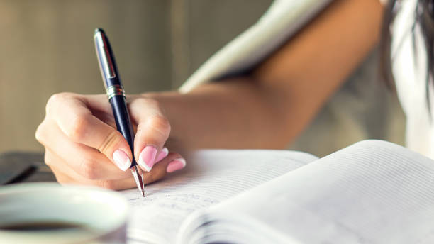 istock Young woman right hand writing plans on small diary in cafe close up 1249846219
