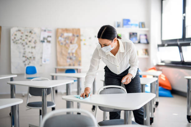 istock Teacher back at school after covid-19 quarantine and lockdown, disinfecting desks. 1249846319