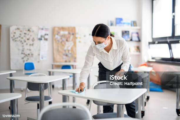 Teacher Back At School After Covid19 Quarantine And Lockdown Disinfecting Desks Stock Photo - Download Image Now