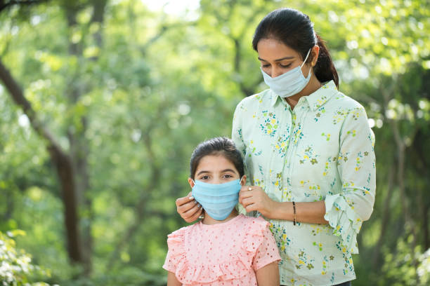 istock Loving mother and daughter with protective face mask at park 1249847493