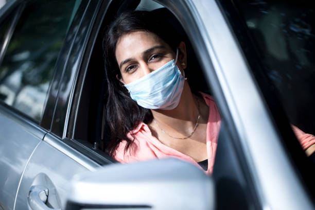 woman driving a car with face mask - india car people business imagens e fotografias de stock