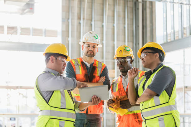 construction workers looking at digital tablet - serious african ethnicity mid adult bright imagens e fotografias de stock