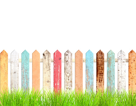 Rustic wooden fence and green grass. Old fence with vintage boards with cracked paint of red, white, brown, orange and blue color. Isolated on white background. 3d render