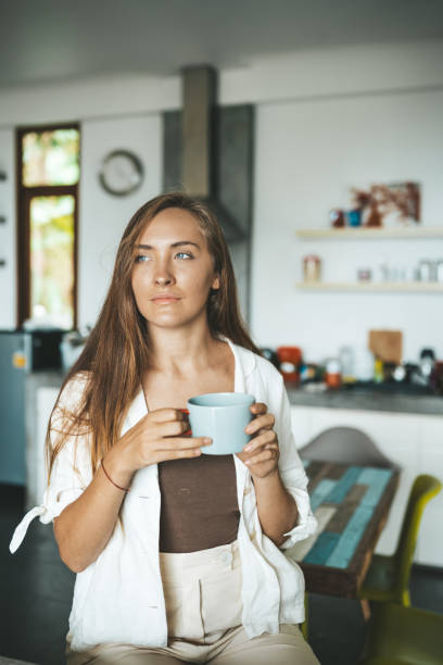 istock Woman sitting in the kitchen and drinking coffee 1249849727