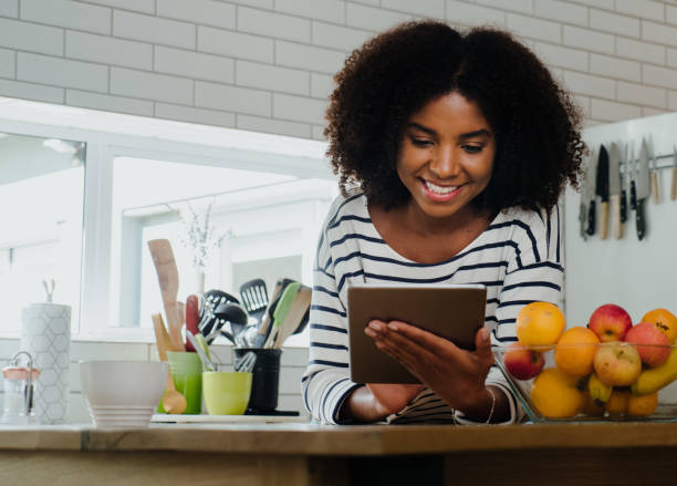 istock Beautiful female browsing recipe on digital tablet in the kitchen at home 1249850964