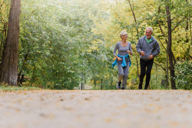 istock Smiling senior couple jogging in the park 1249852473