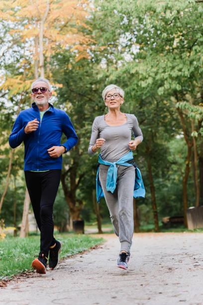 istock Smiling senior couple jogging in the park 1249853319