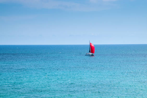 Red ship on red sails. Blue sea and sky on the background.