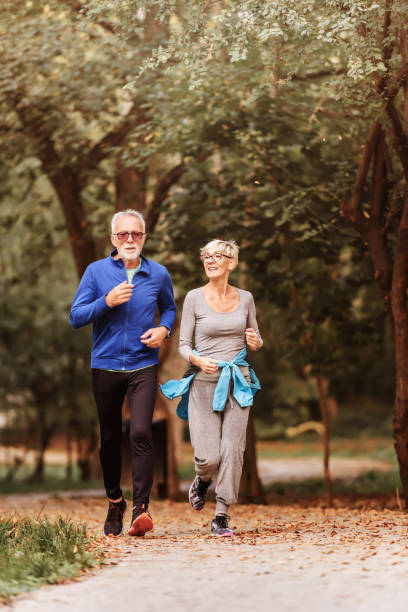 istock Smiling senior couple jogging in the park 1249854939