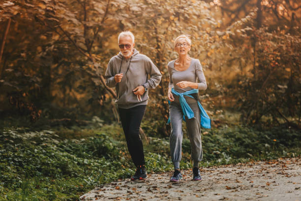 istock Smiling senior couple jogging in the park 1249855000