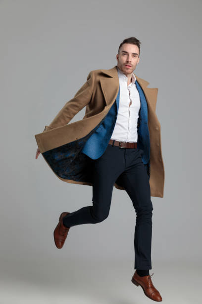 istock attractive young businessman in longcoat jumping 1249855184