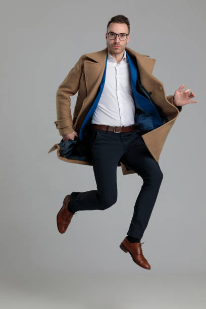 istock smartcasual young guy wearing long coat and jumping 1249855200