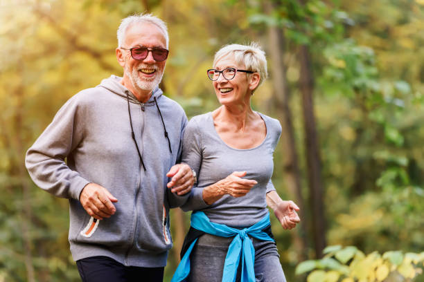 istock Smiling senior couple jogging in the park 1249855341