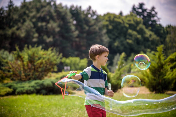 istock Little boy playing with his soap bubbles toy in the park. Child activity. Springtime concept 1249856536