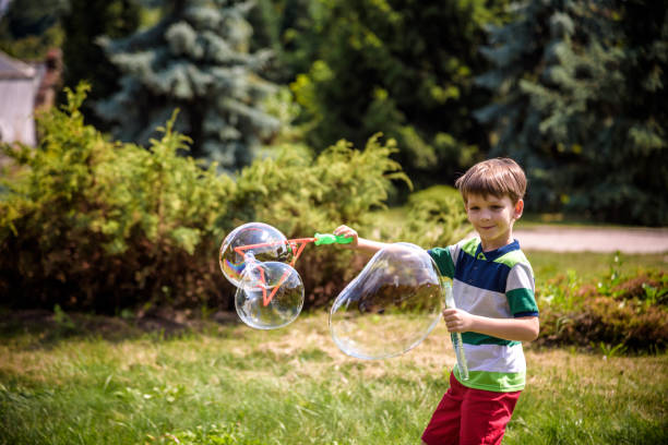 istock Little boy playing with his soap bubbles toy in the park. Child activity. Springtime concept 1249856550