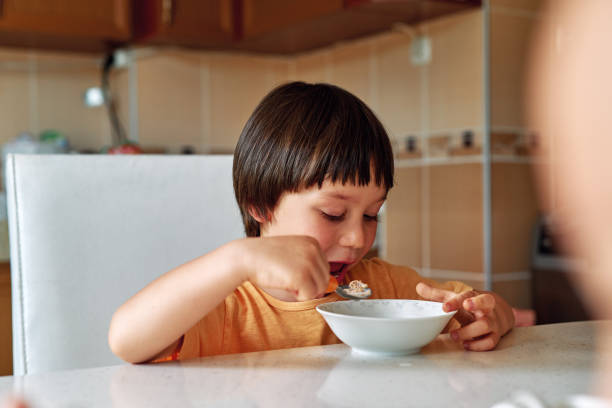 istock 4-5 years old cute child eating corn flakes with milk for breakfast. 1249858629