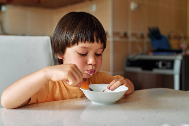 istock 4-5 years old cute child eating corn flakes with milk for breakfast. 1249859222