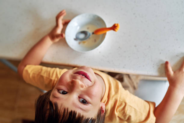 4-5 세의 귀여운 아이가 아침 식사로 우유와 옥수수 조각을 먹고. - little boys breakfast caucasian child 뉴스 사진 이미지
