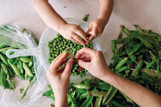 istock Mother and child preparing green pea at kitchen together 1249860289