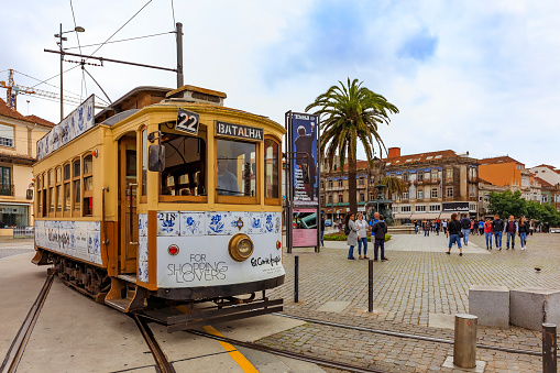 Porto, Portugal - May 30, 2018: View of a typical street in the old town city center with a classic retro tourist tram car and people walking around