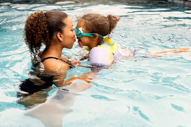 Mixed-race sisters having fun in the backyard pool.