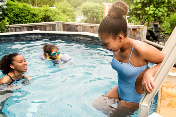 istock Mixed-race sisters having fun in the backyard pool. 1249864279