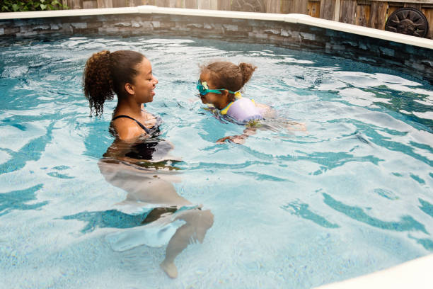 istock Mixed-race sisters having fun in the backyard pool. 1249864332