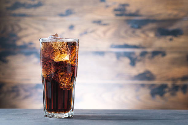 istock Cold fizzy drink with ice cubes on wooden background 1249864457