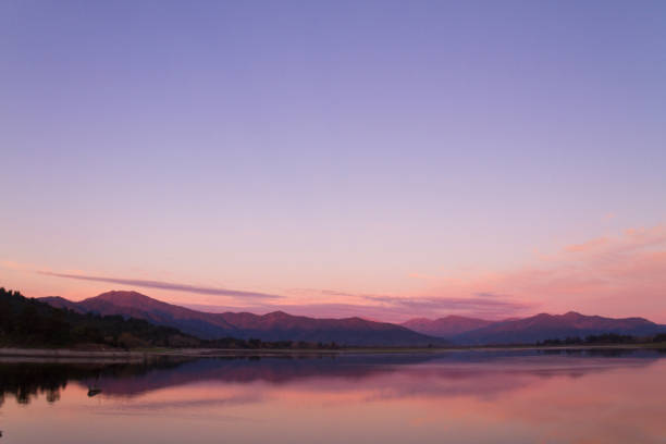 schöne patagonien landschaft der anden bergkette mit hohen bergen mit beleuchteten gipfeln, steinen im bergsee, reflexion, violetter himmel und nebel bei sonnenuntergang. - see mirror lake stock-fotos und bilder