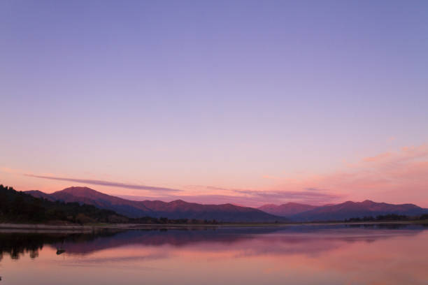 hermoso paisaje patagónico de la cordillera de los andes con altas montañas con picos iluminados, piedras en el lago de montaña, reflexión, cielo violeta y niebla al atardecer. - bariloche patagonia argentina lake fotografías e imágenes de stock