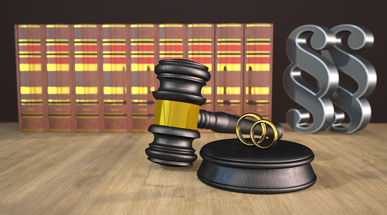 Judge gavel with wedding rings, books and paragraphs on the wooden table. 3d illustration.