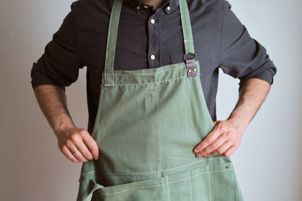 un uomo in grembiule da cucina. lo chef lavora in cucina. cuocere in uniforme, abbigliamento protettivo. lavoro nel servizio di cibo. cucina professionale. grembiule in tessuto verde, abbigliamento casual ed elegante. bel fornaio in posa sul posto di lavor - grembiule foto e immagini stock