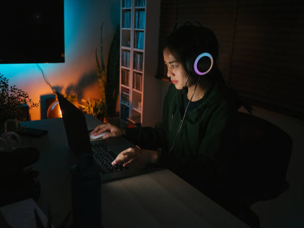 istock Young girl playing computer game on laptop at night 1249868475