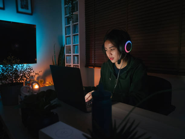 istock Young girl playing computer game on laptop at night 1249868481
