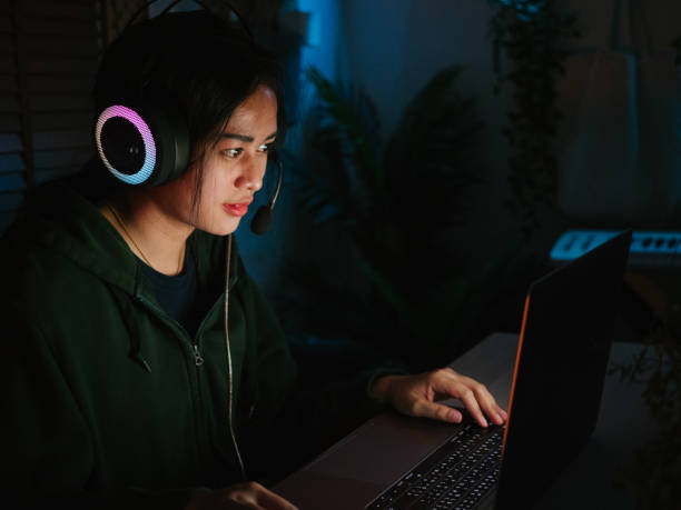 istock Young girl playing computer game on laptop at night 1249868495