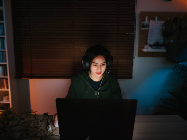 istock Young girl playing computer game on laptop at night 1249868496
