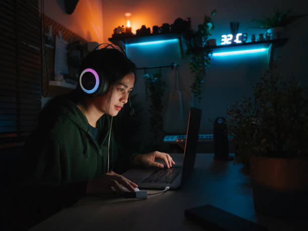 istock Young girl playing computer game on laptop at night 1249868514