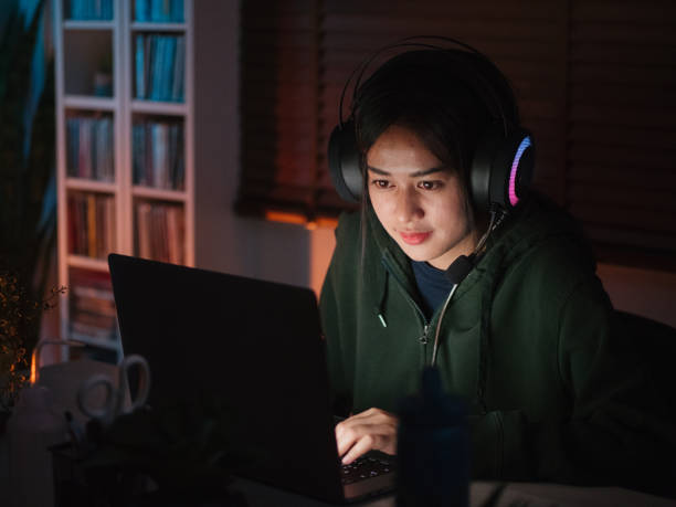 istock Young girl playing computer game on laptop at night 1249868519
