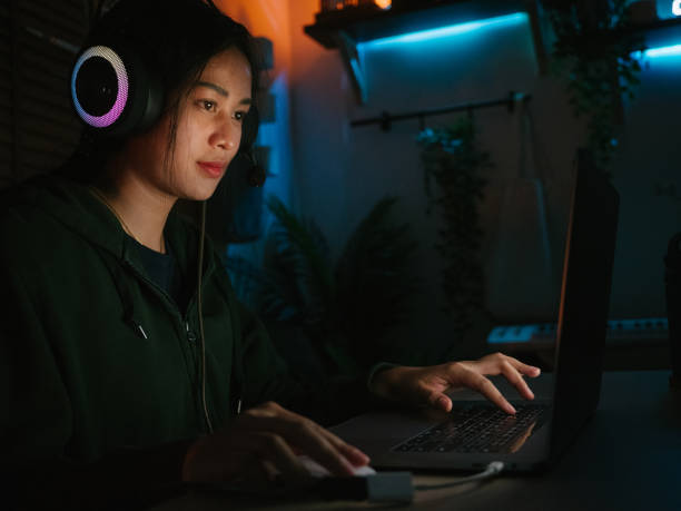 istock Young girl playing computer game on laptop at night 1249868534