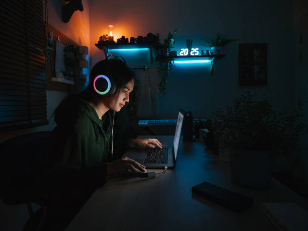 Young girl playing computer game on laptop at night Teenager asian woman playing games on a laptop at home computer hacker spy computer crime laptop stock pictures, royalty-free photos & images