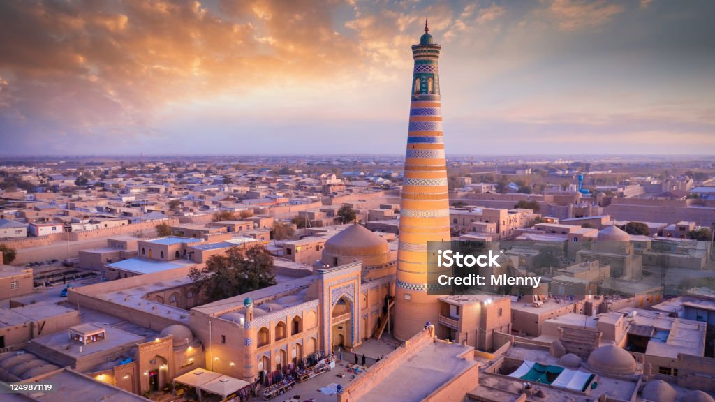 Khiva Sunset Twilight Panorama Islam Khoja Minaret Uzbekistan Aerial Panorama of beautiful colorful sunset twilight over the famous old city of Khiva - Xiva - Хива on the Silk Road with iconic islamic Islam Khoja Minaret - tallest Minaret in Uzbekistan. Itchan Kala, Khiva - Chiva, Xorazm Region, Uzbekistan, Central Asia Uzbekistan Stock Photo