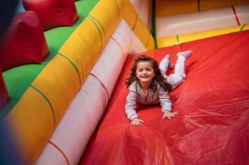 Happy little girl playing in an inflatable playground