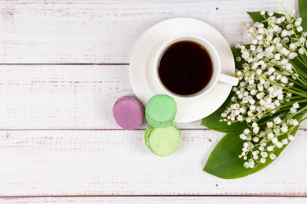 bunte makronen, eine tasse kaffee und lilien des tales auf holzhintergrund, nahaufnahme flach liegen - comfort food high angle view directly above close up stock-fotos und bilder