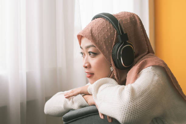 istock Young woman with hijab enjoying music on sofa 1249874206