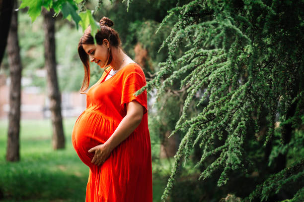 pregnant woman touching her big belly and walking in the park - abdomen gynecological examination women loving imagens e fotografias de stock
