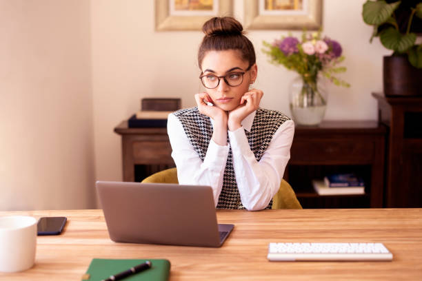 istock Thinkinh young woman looking thoughtfully while sitting at desk and working 1249877807