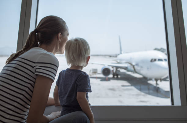 Mother and child at airport waiting to board airplane. Family travel concept. airports canada stock pictures, royalty-free photos & images