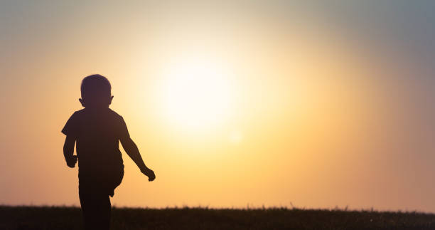 istock Happy little child running playing a in field at sunset. 1249879071