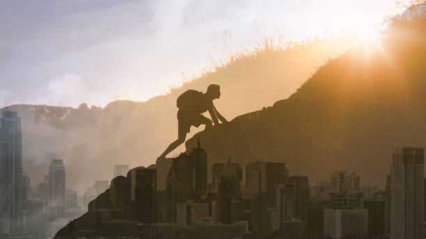 istock Man climbing up mountain against city background. 1249879106